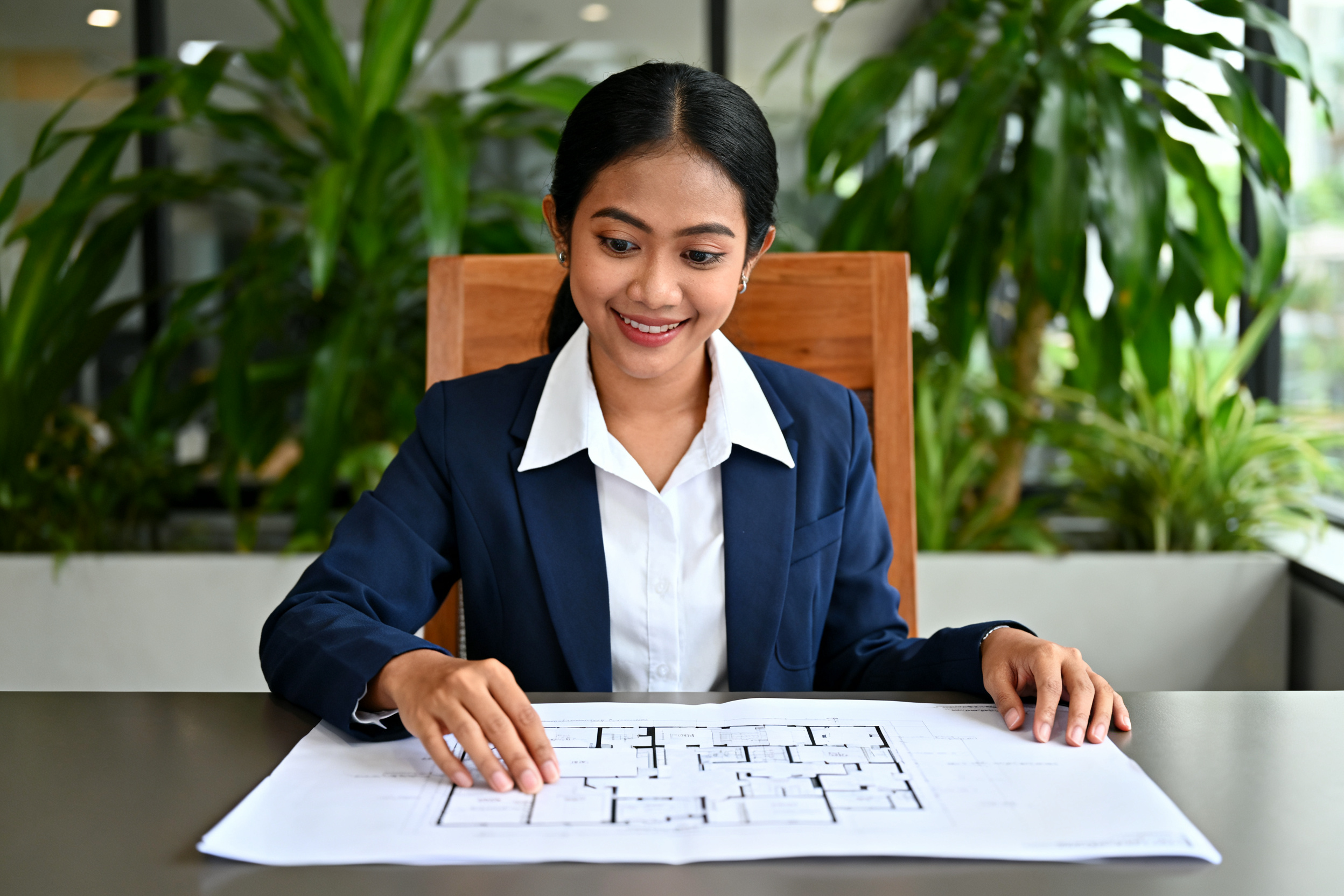 Strategi transisi ESG praktis ditunjukkan oleh wanita Indonesia memeriksa rencana floor plan di meja kantor